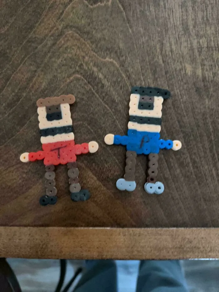 Two colorful plastic bead figures on a wooden surface, part of wholesome pics of dads embracing fatherhood creativity.
