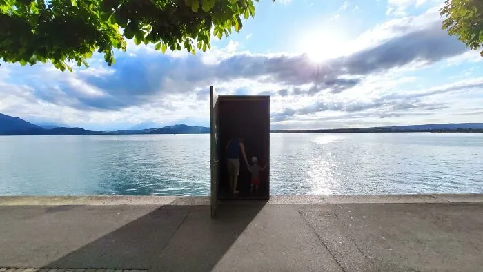 Strange photos featuring an open doorway standing alone by a lake with people inside the shadow frame