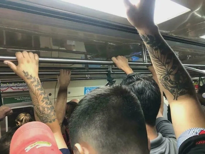 Strange photos of two subway passengers with identical leaf tattoos holding the overhead bar.