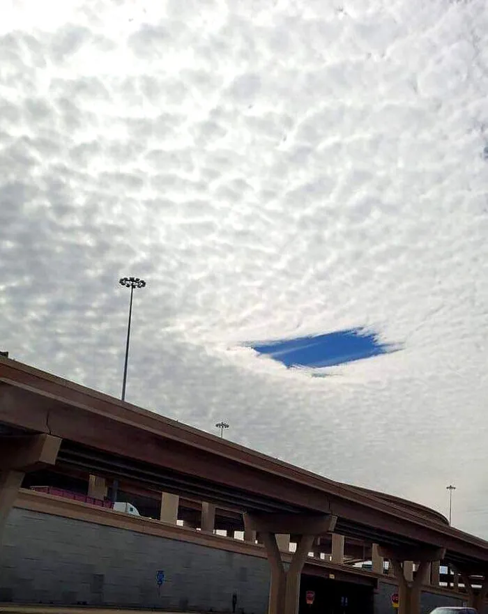 A rectangular hole in the clouds over a highway, one of many strange photos of optical illusions