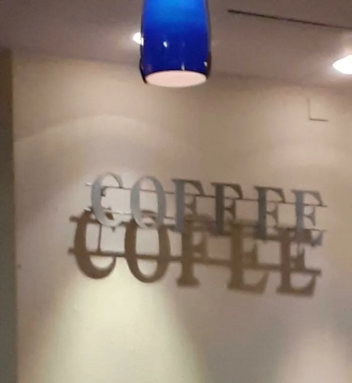 A sign shadow spelling cofle under a light, representing strange photos of everyday glitches