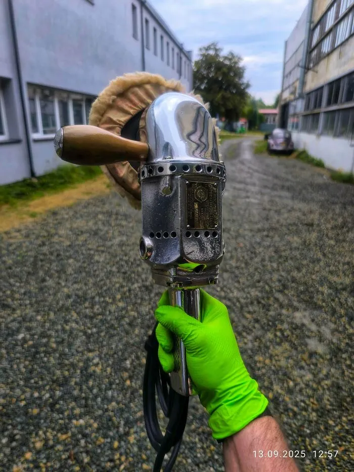 Hand holding a vintage chrome car buffer polishing tool showing retro gadgets aesthetic