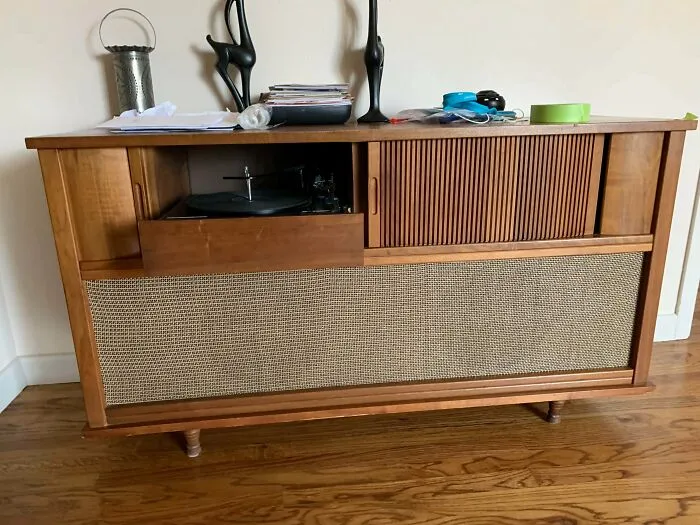A mid-century modern wooden stereo console featuring a built-in record player, an example of retro technology.