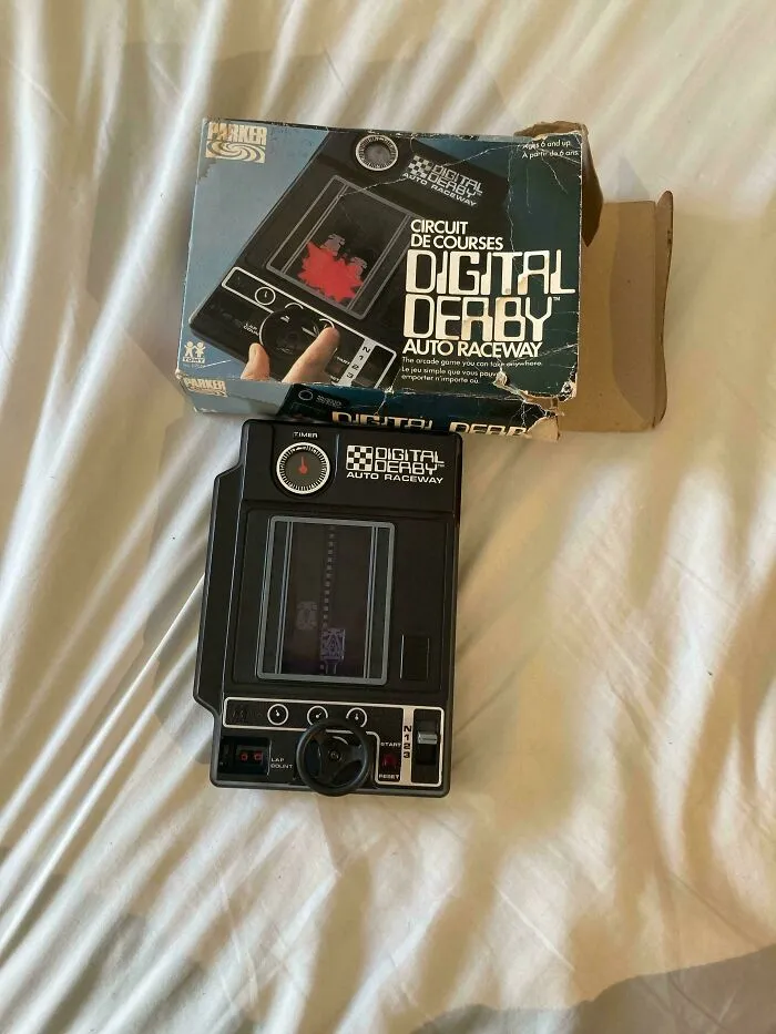 A Parker Digital Derby Auto Raceway electronic handheld game next to its box, showcasing vintage retro gadgets.