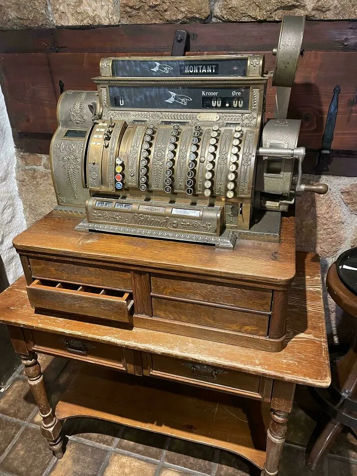 An ornate vintage cash register standing on a wooden cabinet as an example of retro gadgets technology.