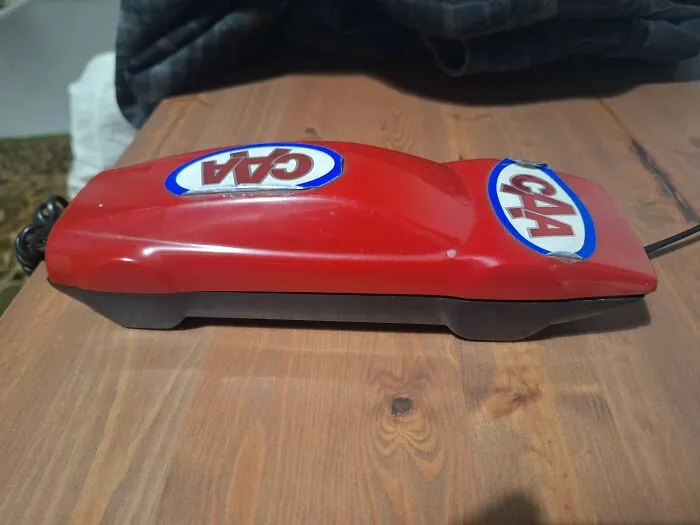 A red race car shaped telephone representing vintage home retro gadgets and technology.