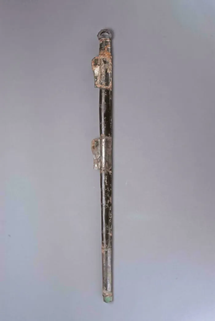 Long ancient metal artifact with corroded patina and detailed fittings