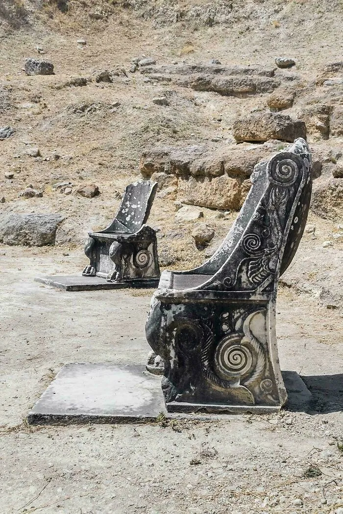 Ancient stone chairs with intricate spiral carvings archaeological artifact