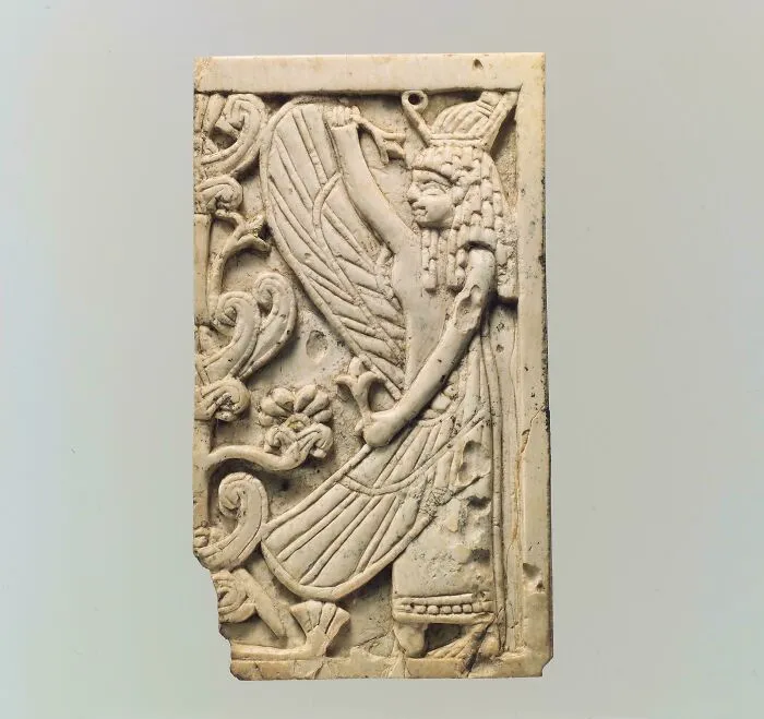 Carved ivory relief of an ancient winged figure and floral motifs