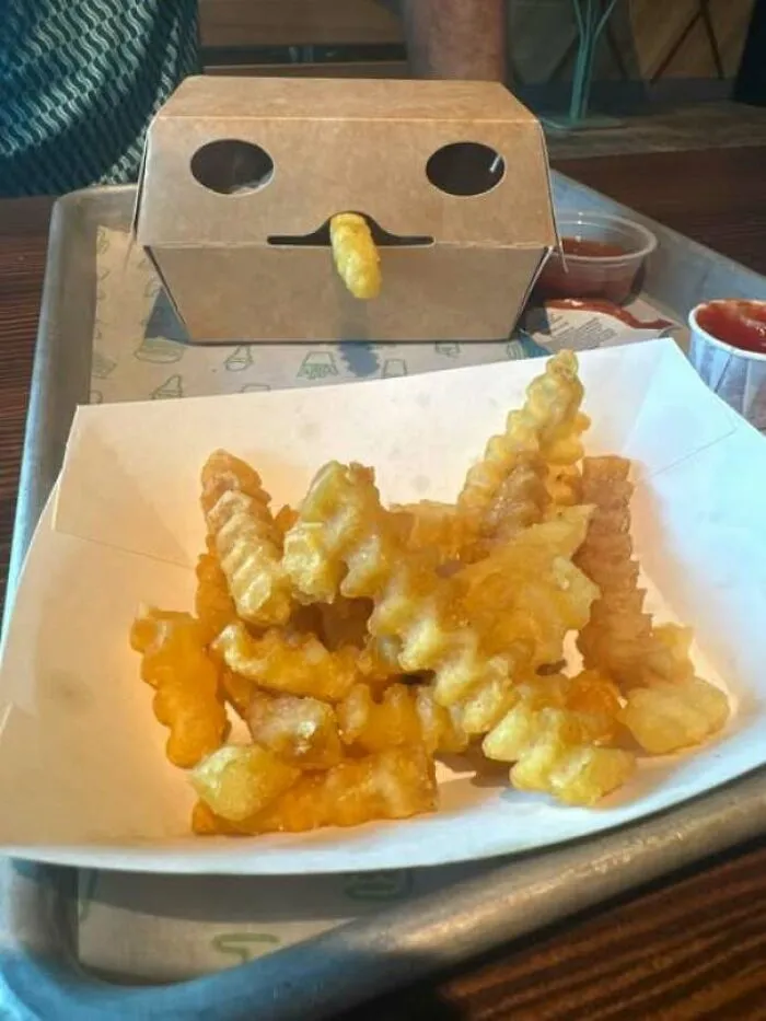 Takeout box and fries creating a face with fries as nose and eyes