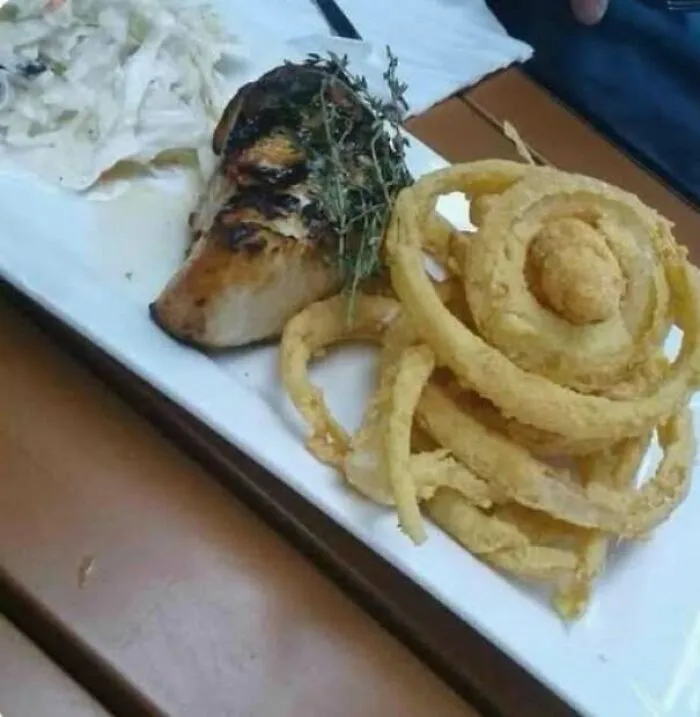 Food plate with onion rings and grilled meat resembling a dog face staring
