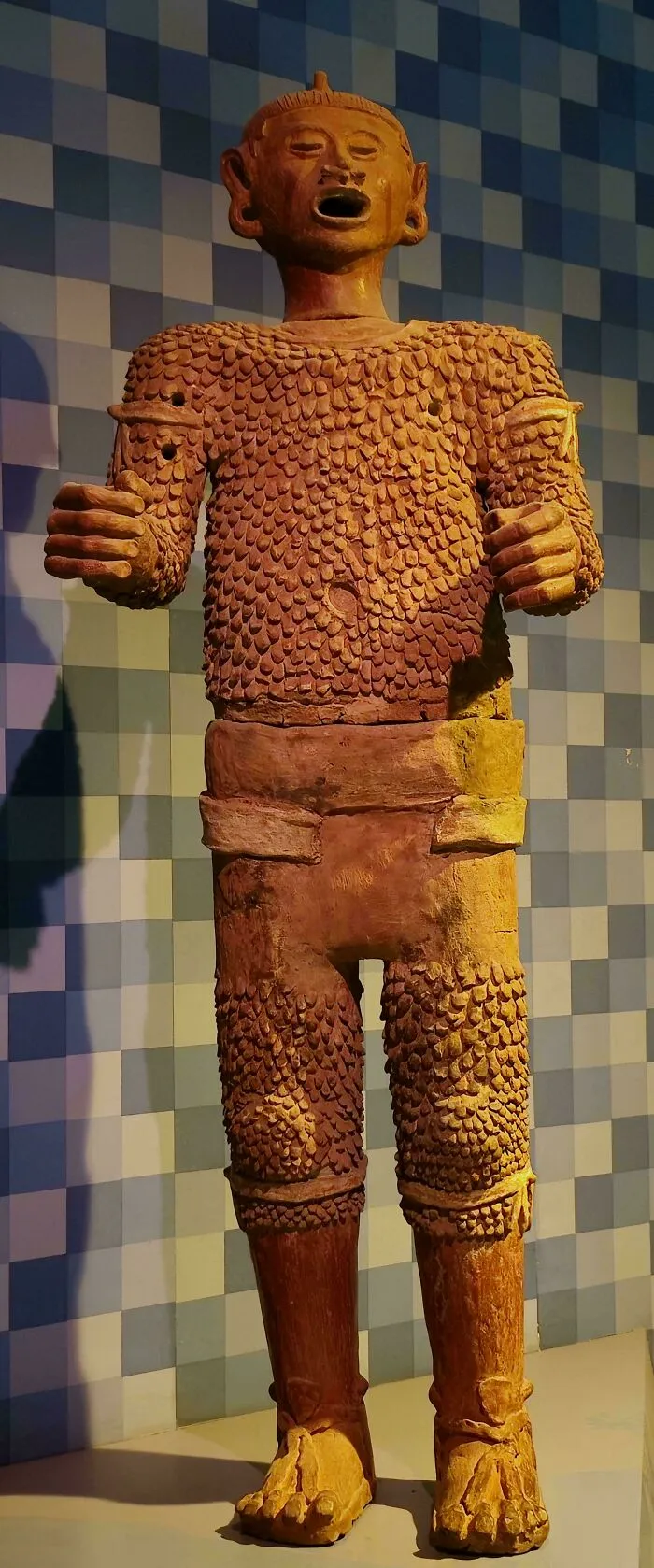 Large terracotta warrior statue with textured armor and open mouth