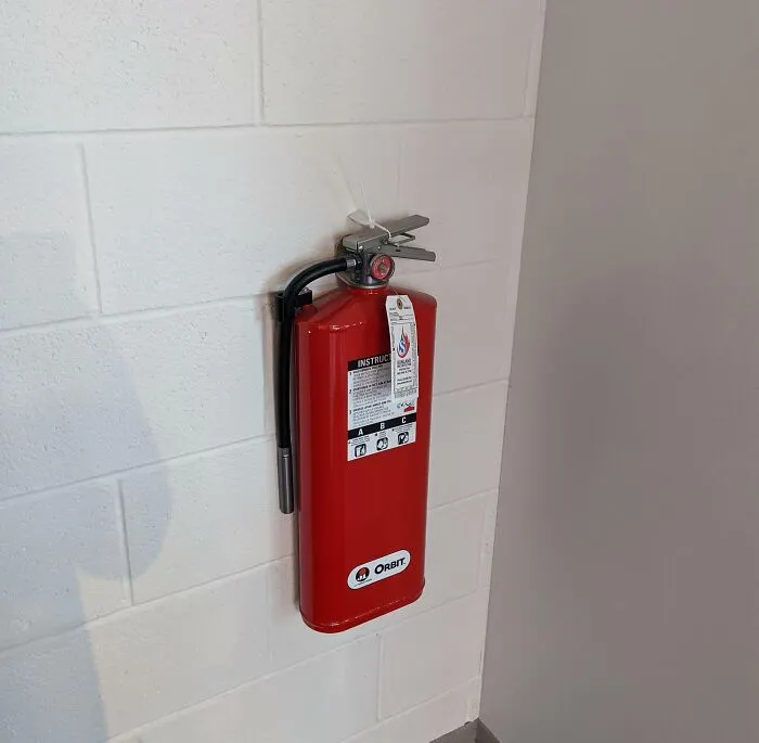 A red fire extinguisher mounted on a white cinder block wall looks like one of these strange photos.