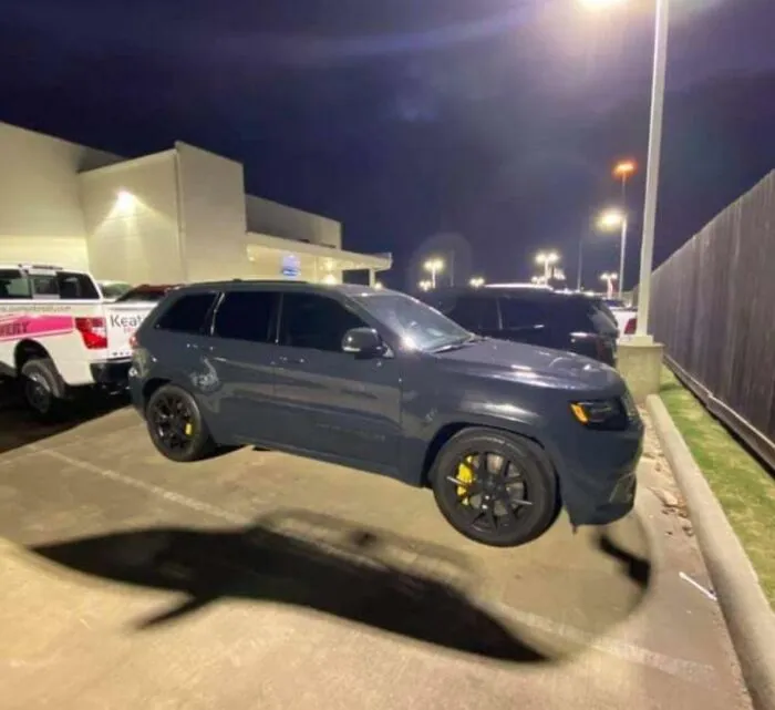 A grey SUV parked outdoors looking like a strange floating object in strange photos.