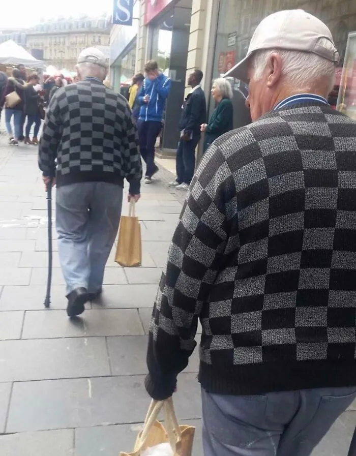 Two men wearing identical checkered sweaters and caps walking down a street, looking like strange photos in real life.