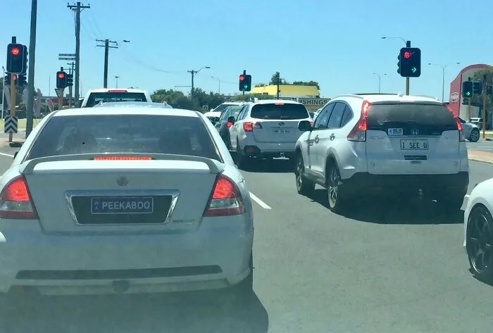 White cars with license plates PEEKABOO and I SEE U in traffic, captured in strange photos.