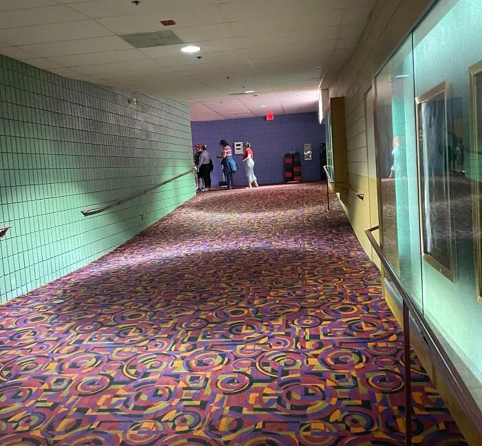 An empty indoor hallway with patterned carpet, evoking strange photos of glitchy surreal spaces.