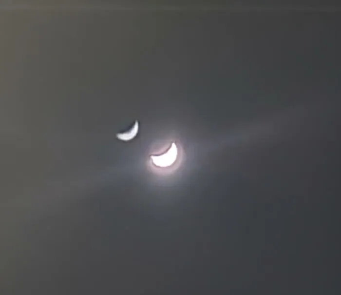 Two crescent moons visible in a hazy sky, looking like strange photos of a surreal astronomical anomaly.