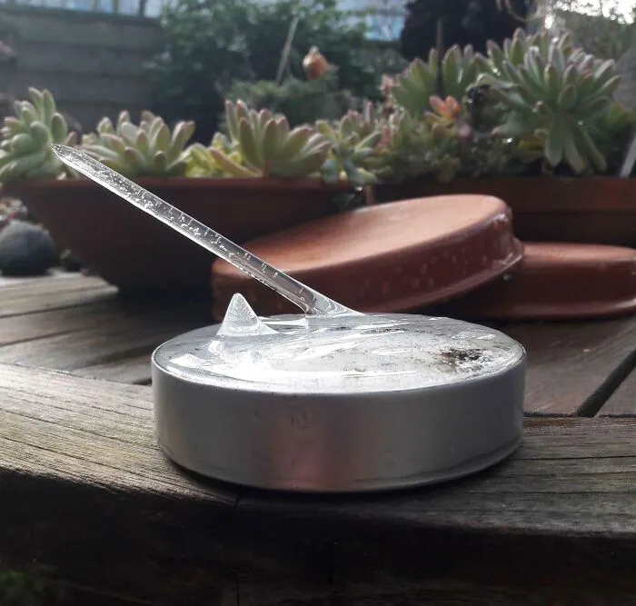 An ice spike growing out of a frozen container, captured in a collection of strange photos.
