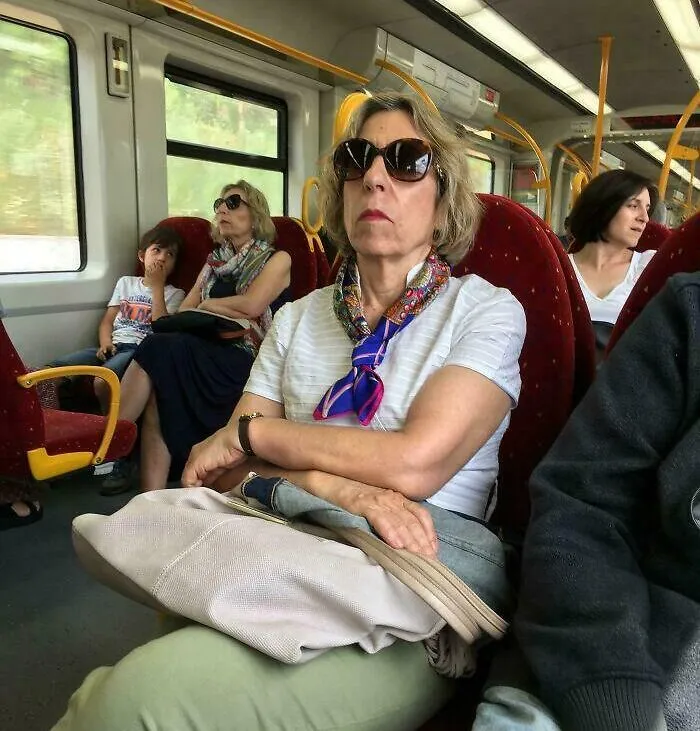 Woman in sunglasses on a train sitting near an almost identical passenger, resembling strange photos of a glitch.