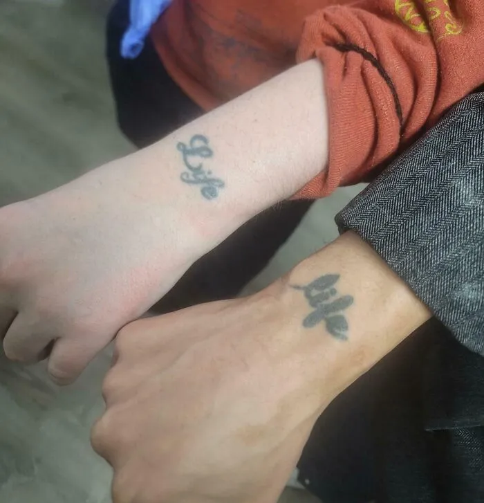 Close-up of two wrists with identical Life tattoos displaying strange photos and odd coincidences.
