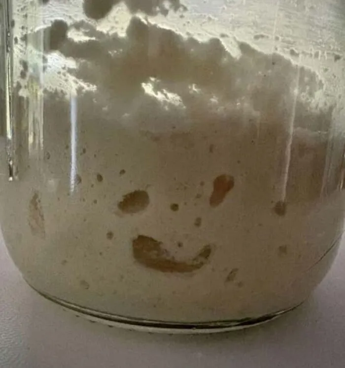 Sourdough starter in a jar resembling a smiling face