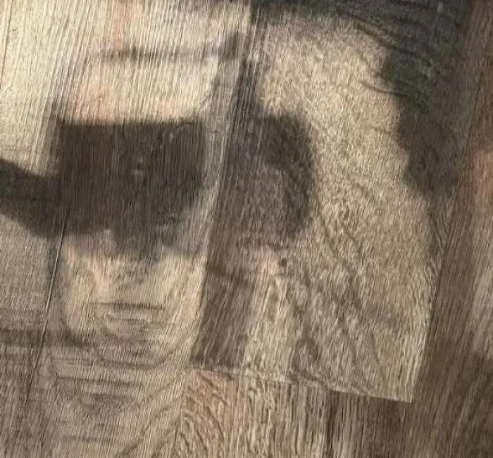 Shadow on wooden floor creating illusion of a staring face