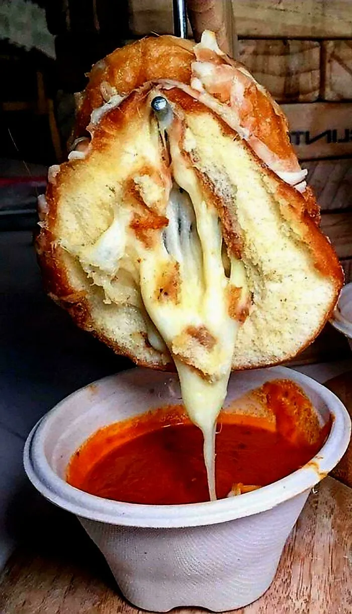 Cheesy bread dripping into tomato soup, a bizarre example of questionable food combos.