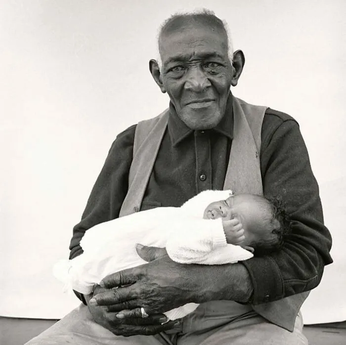 Black and white photo of elderly man holding baby in his arms