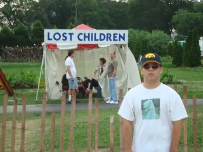 A man posing in front of a Lost Children sign in the background