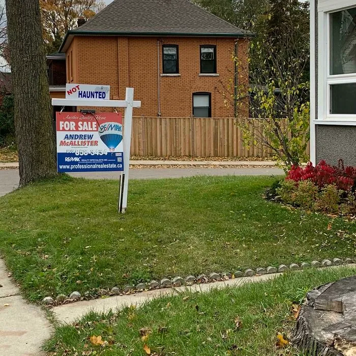 A sign on a lawn says NOT HAUNTED where something in the background completely hijacked the moment