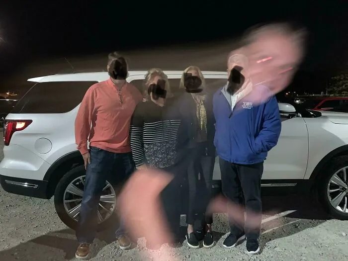 A blurred hand and face sweep across a family photo hijacked by the background at night