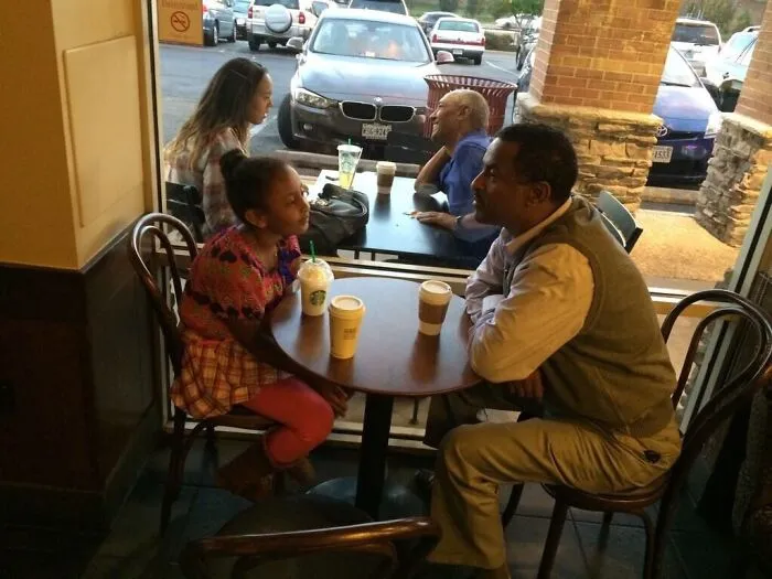 Customers at a coffee shop sitting by a window while people outside mimic their poses