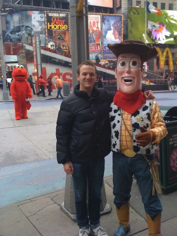 Woody mascot stands with a tourist in Times Square, while Elmo watches in the background.