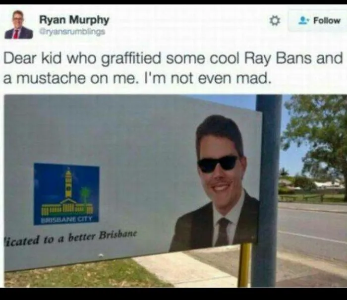 Political billboard of a man modified with drawn-on sunglasses, showcasing a clever act of vandalism.