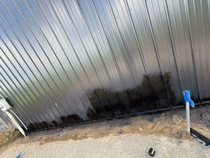 A black metal wall stained at the bottom during a botched attempt to improve and renovate their homes.
