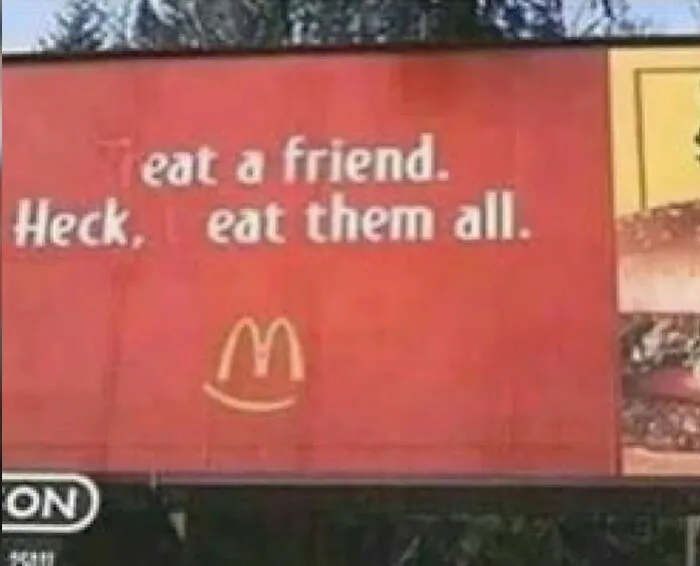 Humorous vandalism on a McDonald's billboard where the letter T is blacked out to say Eat a friend