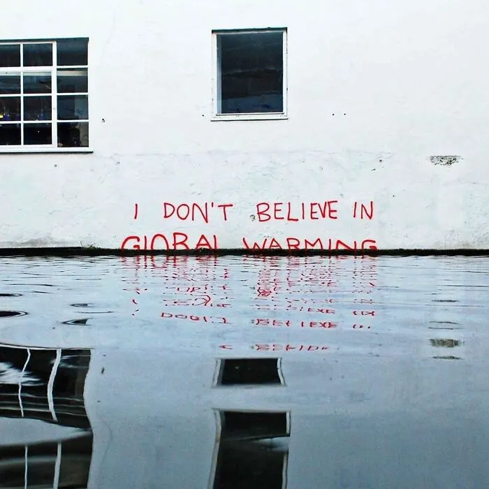 Clever vandalism showing I DON'T BELIEVE IN GLOBAL WARMING graffiti half-submerged in rising water
