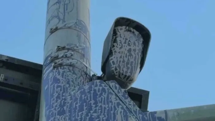 Public art vandalism featuring a speed camera covered in paint to look like a masked figure.