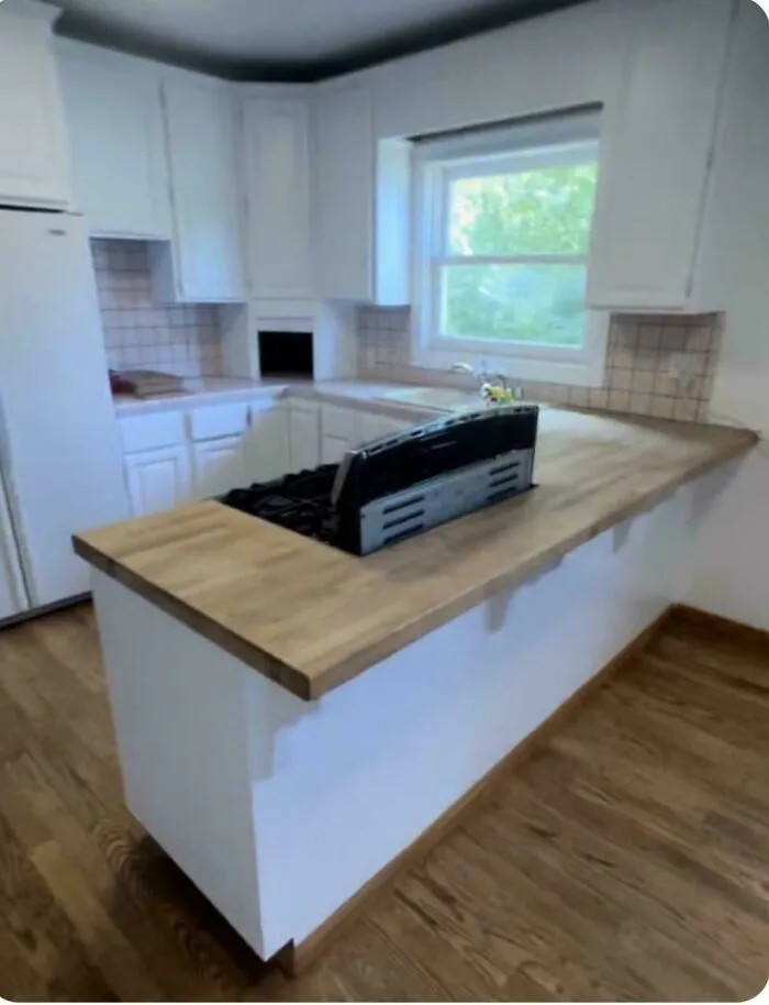 An awkwardly placed stove on a wooden countertop kitchen island during a home renovation.