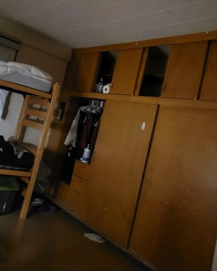 A messy college dorm room with bunk beds and wooden closets from crazy roommate stories