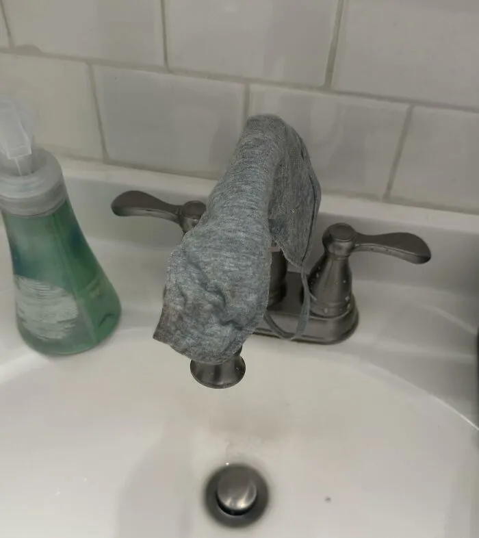 A dirty cloth mask left hanging on a bathroom sink faucet in funny roommate stories