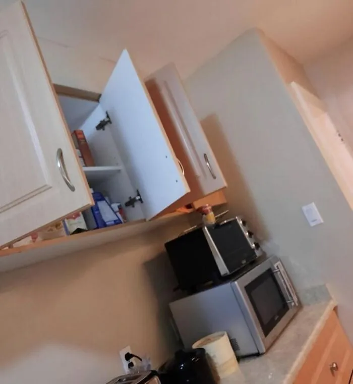 Open kitchen cabinet doors above a microwave, highlighting typical roommate stories and habits.