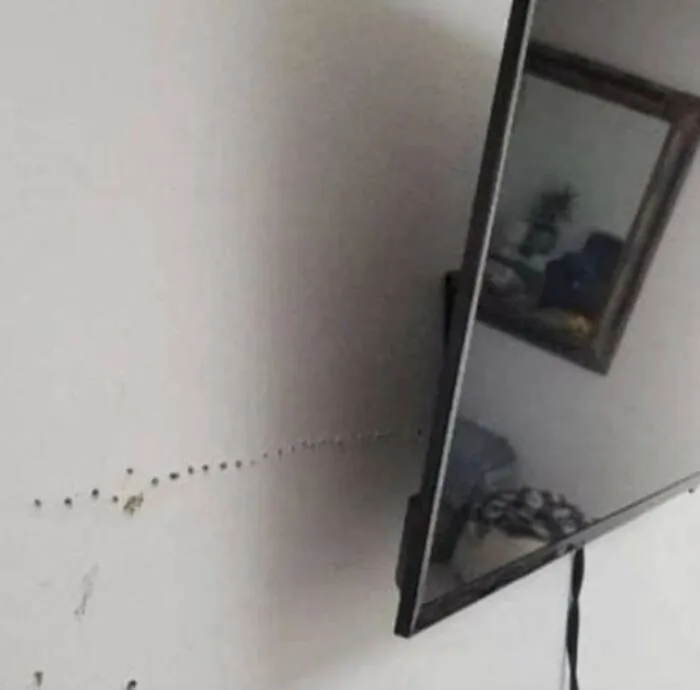 A wall covered in multiple drill holes from a failed TV mounting home improvement project.