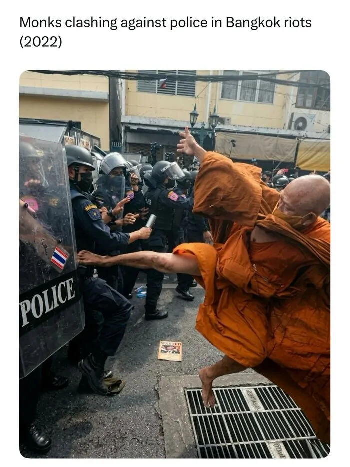 Funny memes action shot of a monk in orange robes performing a flying kick against riot police shields in Bangkok