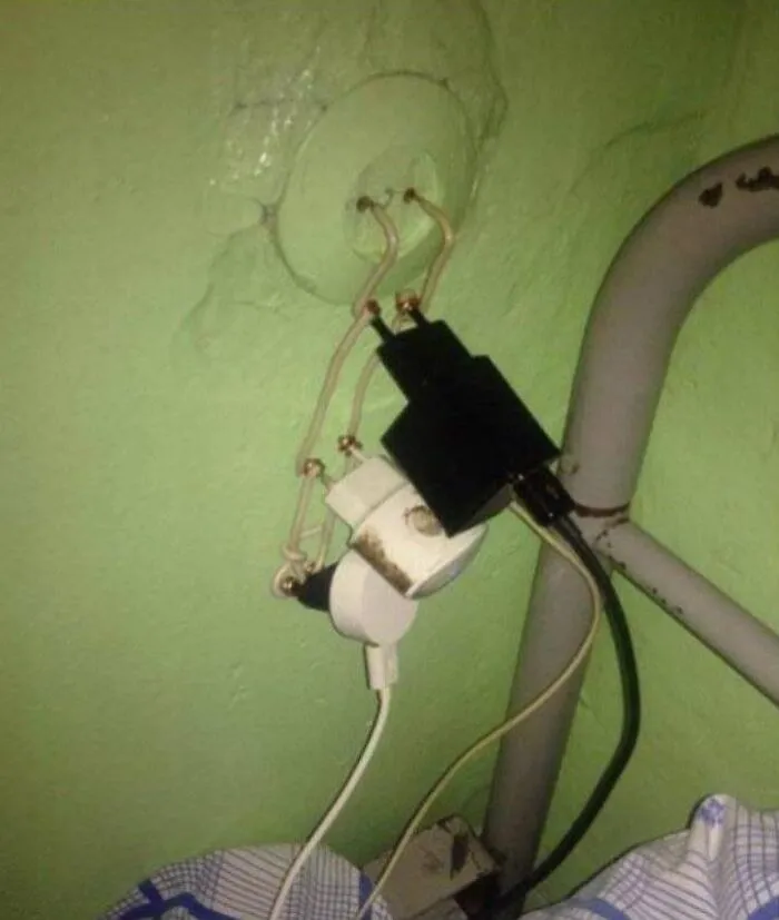 Dumb redneck fixes using exposed wires to connect multiple power plugs to a green wall outlet.