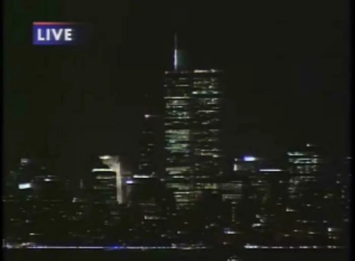 Live news broadcast screen showing the illuminated World Trade Center towers at night in 2001