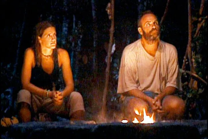 Reality TV show contestants sitting around a campfire in 2001.