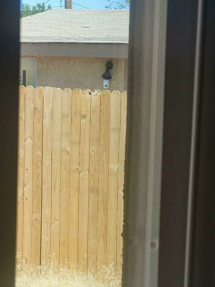 Security camera pointed over a fence line, illustrating infuriating neighbors invading privacy.