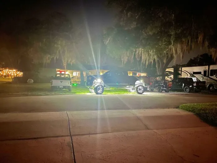Lifted truck with blinding underglow and headlights parked outside at night, showing infuriating neighbors.